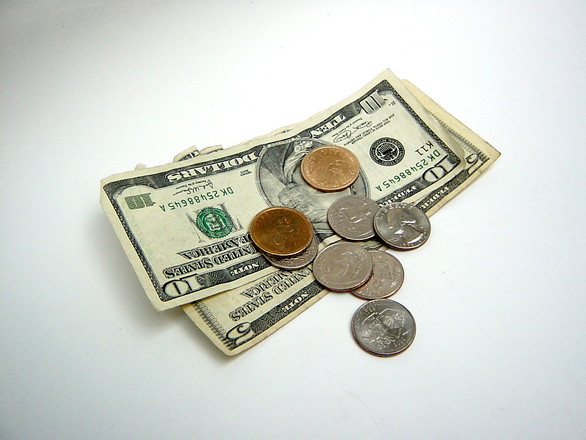 Small stack of cash with some coins on top with a white background